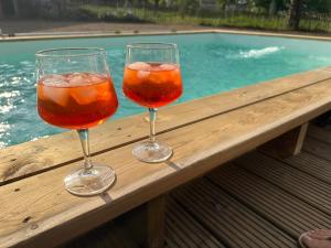 Zwei Weingläser stehen auf einem Holzgeländer neben einem Swimmingpool. in der Unterkunft Envoz-Zen in Héron