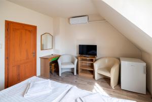 a bedroom with a bed and a desk with a television at Főnix Fogadó in Lenti