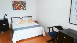a bedroom with a bed and a desk and a painting at Muito espaço e natureza no meio da cidade in Santos +37 photos