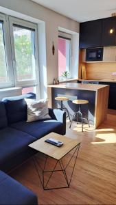 a living room with a blue couch and a kitchen at BLACKWOOD Kitchen in Bratislava