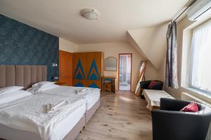 a hotel room with two beds and a chair at Főnix Fogadó in Lenti