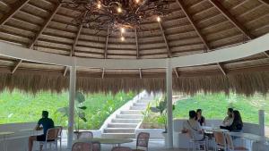people sitting at tables in a restaurant under a straw roof at Coron Cozy Nature Hut in Coron