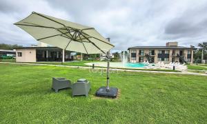 a umbrella and two chairs in a yard with a pool at Lagoon Miramar in Miramar