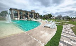 a swimming pool with white chairs and a fountain at Lagoon Miramar in Miramar