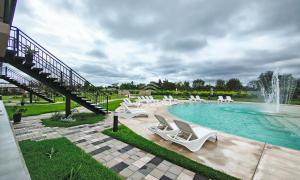 a swimming pool with white chairs and a fountain at Lagoon Miramar in Miramar