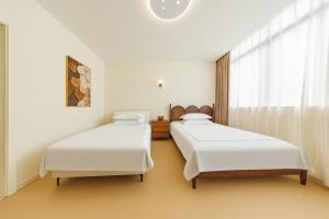 two beds in a room with white walls and a window at Boyi Apartment - Shanghai National Convention and Exhibition Center Branch in Shanghai