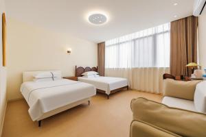 a hotel room with two beds and a couch at Boyi Apartment - Shanghai National Convention and Exhibition Center Branch in Shanghai