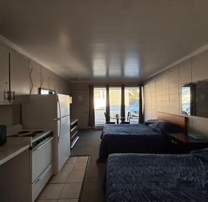 a bedroom with two beds and a kitchen with a refrigerator at Pineapple Inn in North Attleboro