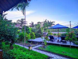 a garden with chairs and an umbrella and trees at RR Cottage in Nusa Penida