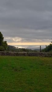a field of grass with the ocean in the background at Cabana Papoila in Colares