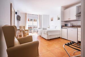 a bedroom with a bed and a kitchen with a couch at Apartamentos Capricho del Mar in Torremolinos
