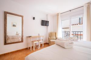 a white bedroom with a bed and a mirror at Apartamentos Capricho del Mar in Torremolinos