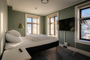 ein Schlafzimmer mit einem Bett, grünen Wänden und Fenstern in der Unterkunft Bakerigården in Lillesand