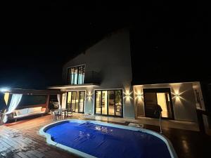 a swimming pool in front of a house at night at Casa campo moderna e confortável in Itatiba