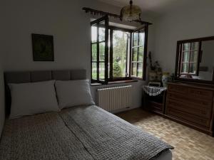 a bedroom with a bed and a dresser and windows at Siedlisko Studzianki in Studzianki Pancerne