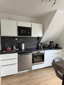 a kitchen with white cabinets and a microwave at Ferienwohnung Ruhepunkt Dessau - zentral nahe Bauhaus und Meisterhäusern - mit gratis WLAN und Parken sowie Komplettküche in Dessau