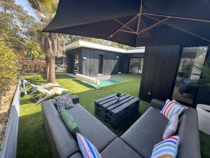 a patio with a couch and a table and an umbrella at Villa bord de mer in Labenne