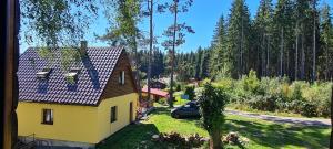 a yellow house with a car parked in a yard at Chata Sandra in Lipno nad Vltavou