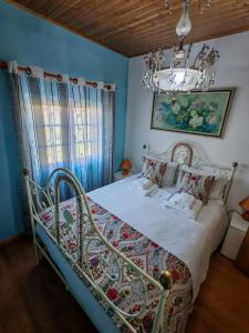 a bed in a blue bedroom with a chandelier at Malhadinhas House in Vila Nova de Paiva