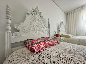 a bedroom with a white bed with a red pillow at Azenha Ah Bô! in Alijó
