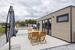 a patio with a table and chairs and an umbrella at NORA Tiny House Bergheider See in Buschmühle