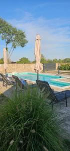 a swimming pool with umbrellas and chairs and a swimming pool at Salaš kod Bobana in Bač