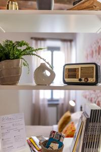 a shelf with a radio and a plant and books at XX Settembre Studio Apartment in Parma