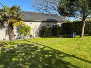 a white house with a palm tree in a yard at Les Mûres in Saint-Lunaire