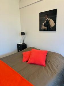 a bed with two red pillows in a bedroom at Les Mûres in Saint-Lunaire