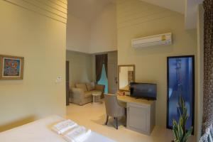 a room with a bed and a desk with a television at Sri Ngachang in Chiang Mai