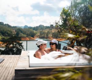 a man and woman sitting in a bath tub on a dock at Porto Marina Hotel in Guatapé