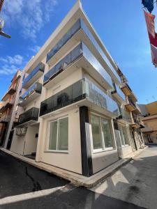 a large white building with windows on a street at Gheloi Room in Gela