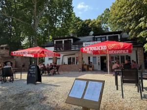 a restaurant with red umbrellas in front of a building at Prenoćište Šoderica in Legrad