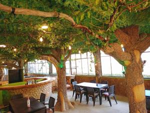 a restaurant with a fake tree and tables and chairs at Hostal Restaurant TOROTORO in Torotoro