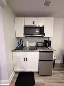 a kitchen with white cabinets and a microwave at Cozy Modern Studio in Philadelphia