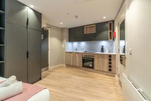 a kitchen with black cabinets and a wooden floor at Stylish & Spacious Studio - Prime Briggate Location -Walk Everywhere in Leeds