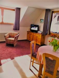 a living room with a table and a television at Ferienhaus im Park in Hinterzarten