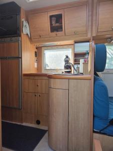 a kitchen with wooden cabinets and a sink in an rv at Le Maillotin en balade in Les Maillys