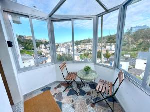 a room with a table and chairs and windows at Atalaya Luarca Apartamentos turísticos in Luarca