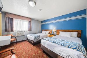 a hotel room with two beds and a blue wall at Travelodge by Wyndham Kanab in Kanab