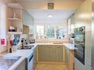 a large kitchen with wooden cabinets and a window at Thimble Cottage - Emsworth in Emsworth