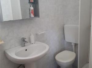 a white bathroom with a toilet and a sink at Apartmani Borić in Orebić