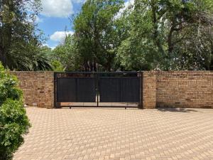 a brick fence with a black gate on it at Highway Haven in Stilfontein