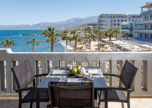 a table on a balcony with a view of the ocean at Arlen Beach Hotel in Hersonissos
