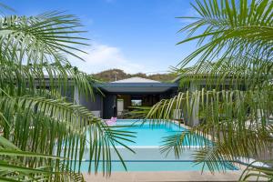 a swimming pool in front of a house with palm trees at Villa lEscale de Sainte Philomène in Saint-Pierre