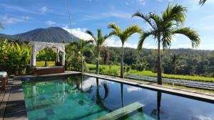 a swimming pool with palm trees and a mountain in the background at Cascadia Rad Villa in Jatiluwih