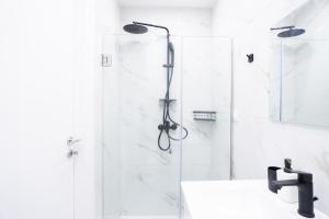 a white bathroom with a shower and a sink at Syntagma Luxury Apartment in Athens