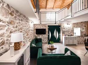 a living room with green chairs and a stone wall at La Felicita in Gornji Zemunik