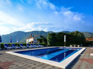 a swimming pool with chairs and umbrellas at Villa Nature Retreat in Gruda +16 photos