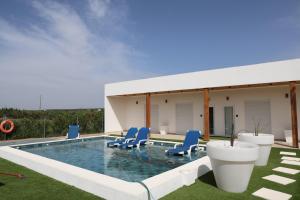 a swimming pool with blue chairs and a house at Olivale Villas in Campo Maior